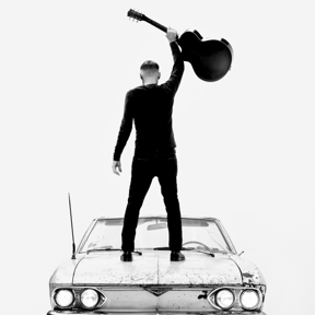 Bryan Adams lifting a guitar over his head