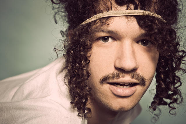 Darwin Deez with a band around his head looking into the camera