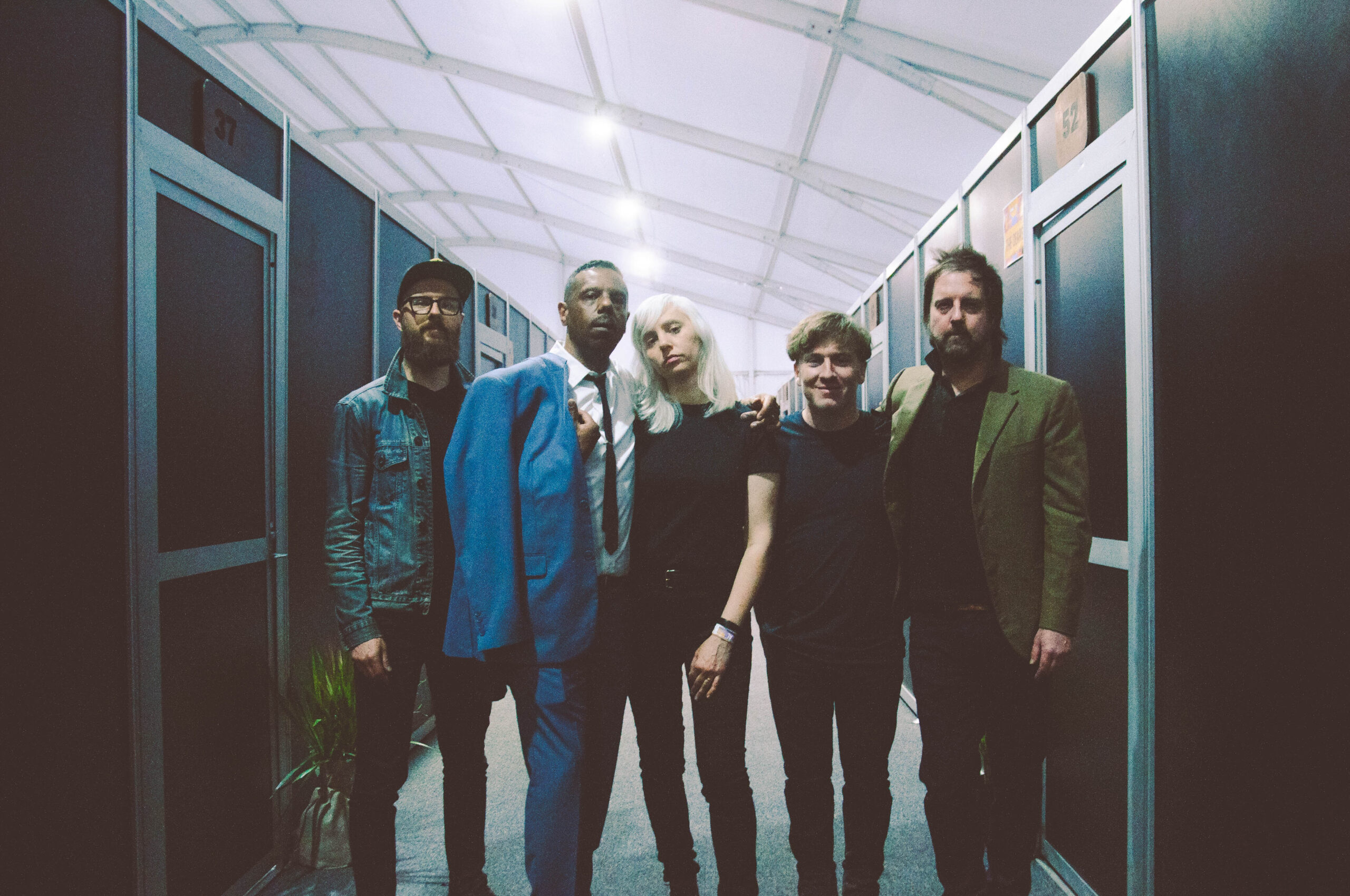 The Dears standing in a line in a corridor of doors