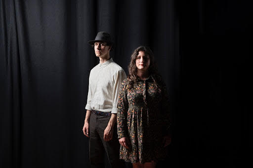 Unthank:Smith duo stood in front of a black curtain looking at the camera.