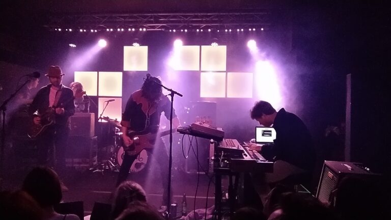 The coral band singing and playing guitars on stage at Future Yard in Birkenhead