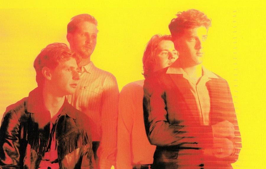 The circa wave band (4 members) all looking to the right and covered in a yellow red glow