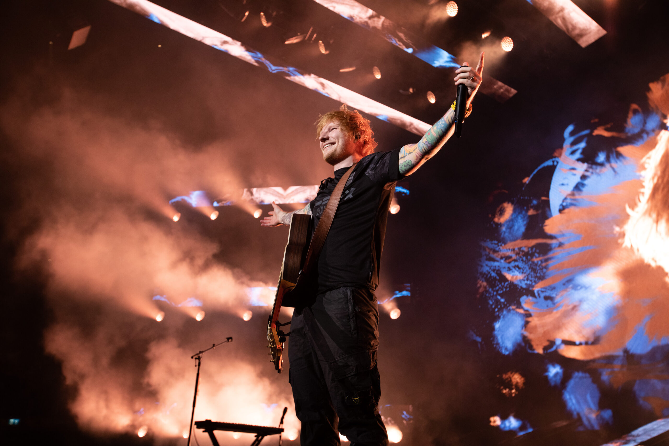 Ed Sheeran stood on stage with his arms outstretched and ticker tape flying around in the air