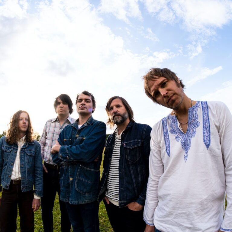 The hanging stars stood in a line on grass with blue skies and white wispy clouds behind them
