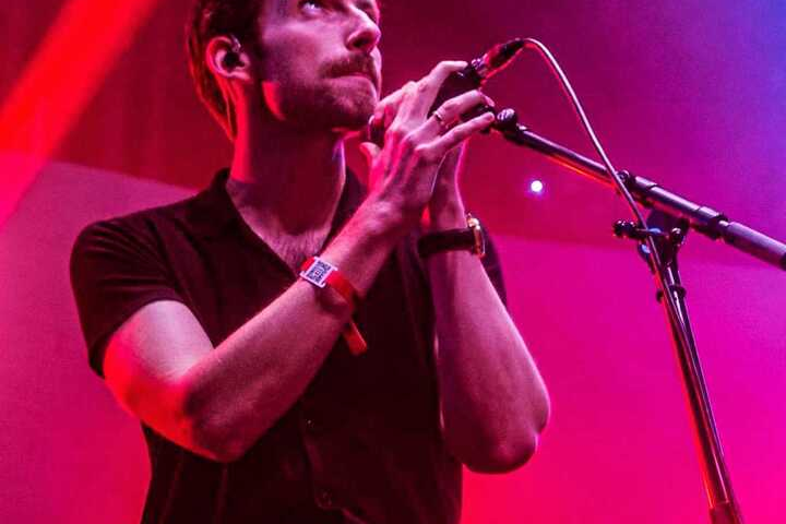 Red rum club lead singer holding microphone and looking up to the sky