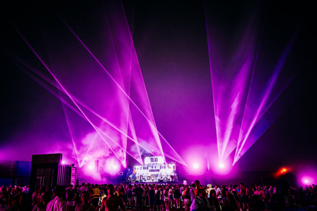 Boardmasters main stage with purple lights shining out from it and a crowd watching