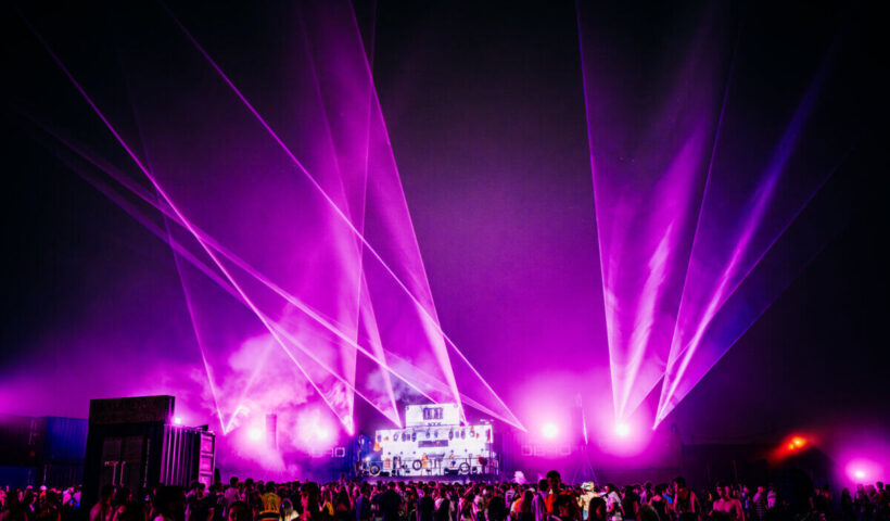 Boardmasters main stage with purple lights shining out from it and a crowd watching