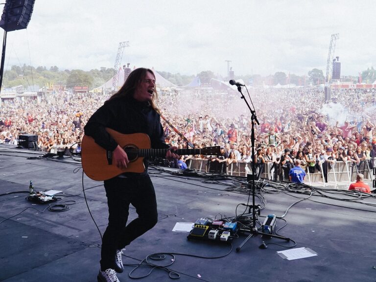 Jamie webster on stage at a festival with his guitar