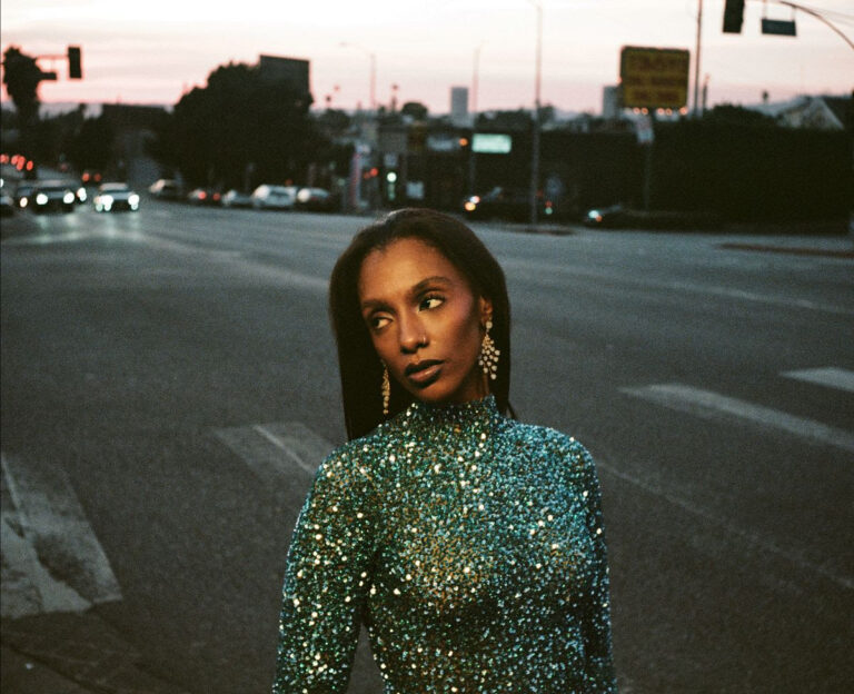 Mereba in a green sparkly top stood on a road with traffic behind her