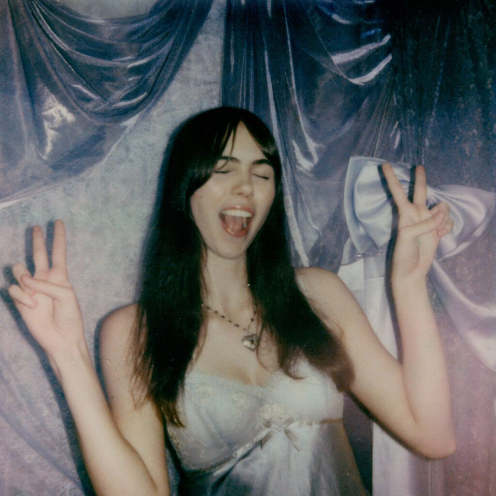 A girl making a peace sign with both hands and laughing