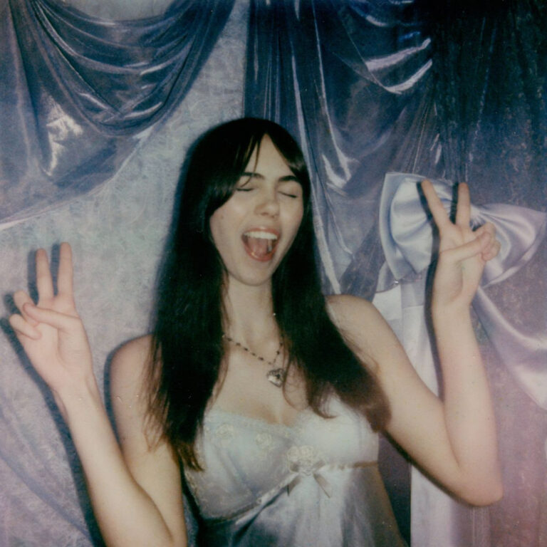 A girl making a peace sign with both hands and laughing