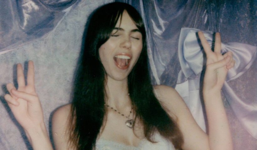 A girl making a peace sign with both hands and laughing