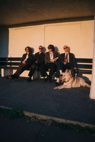 The Royston club sat on a bench at sunset with a dog next to them