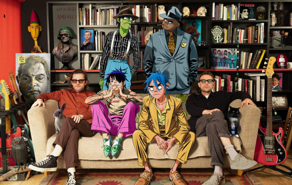 Gorillaz say on a sofa with Damon Albarn in a room full of books, art and guitars