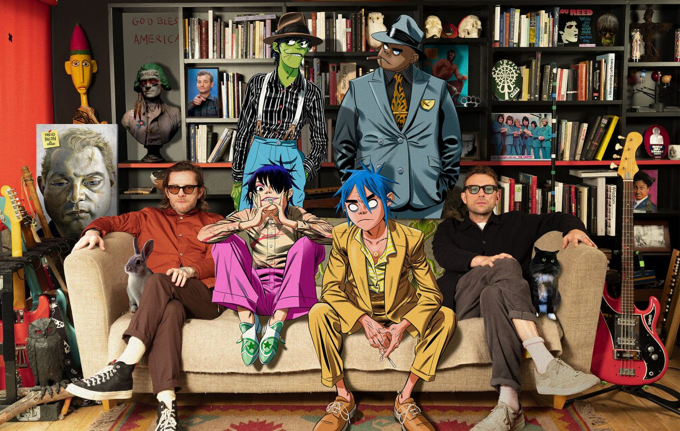 Gorillaz say on a sofa with Damon Albarn in a room full of books, art and guitars