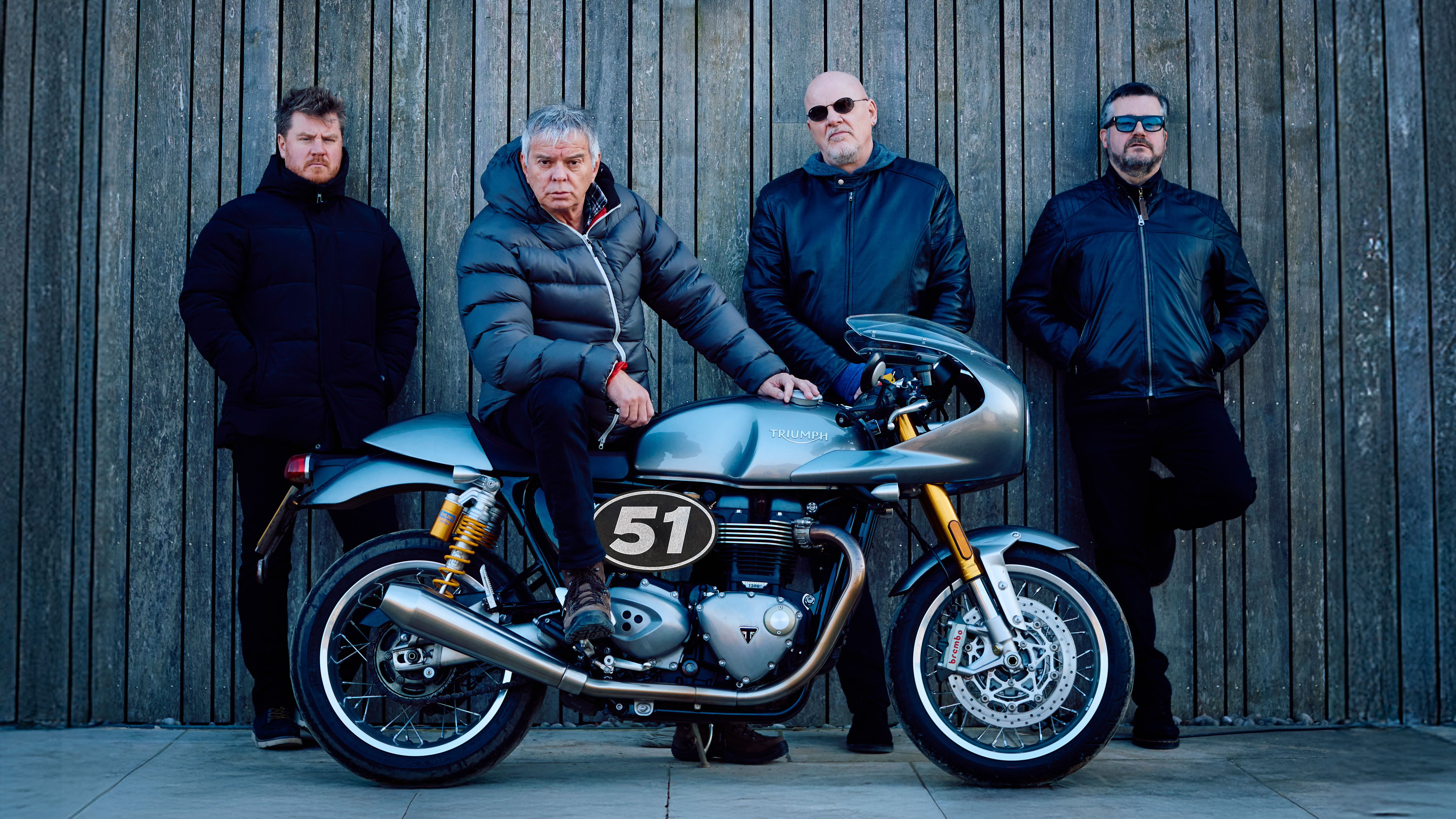 The stranglers stood in front of a motorcycle that has the number 51 on it