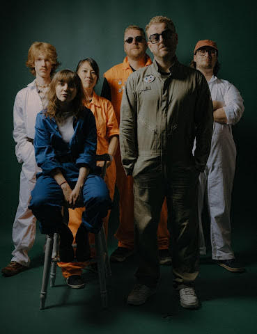 Hello Cosmos stood in a group with one of the female band on a stool