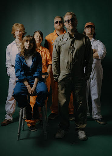 Hello Cosmos stood in a group with one of the female band on a stool