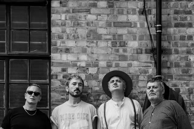 Babyshambles stood by a wall looking up into the sky