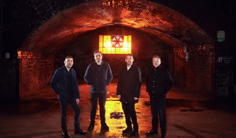 Starsailor standing in an underground venue with a bright yellow light behind them