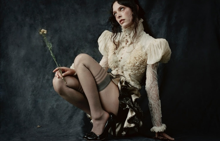 Holly Humberstone sat holding a dead flower in gothic clothes