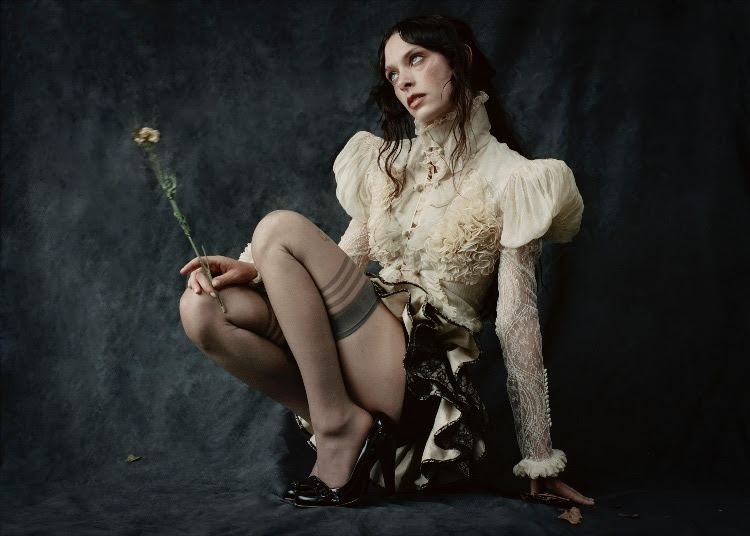 Holly Humberstone sat holding a dead flower in gothic clothes