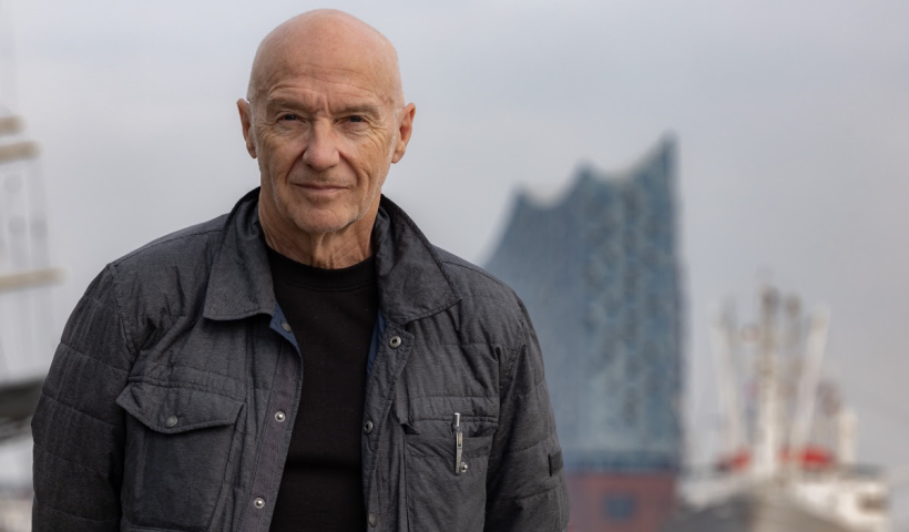 Midge Ure in front of a large building which is in the background