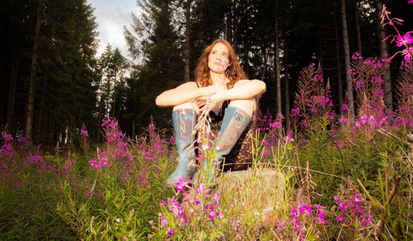 Kate Nash sitting in a wood with wellies on
