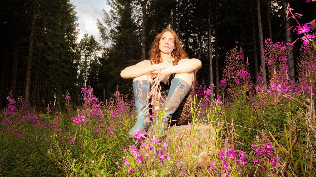 Kate Nash sitting in a wood with wellies on